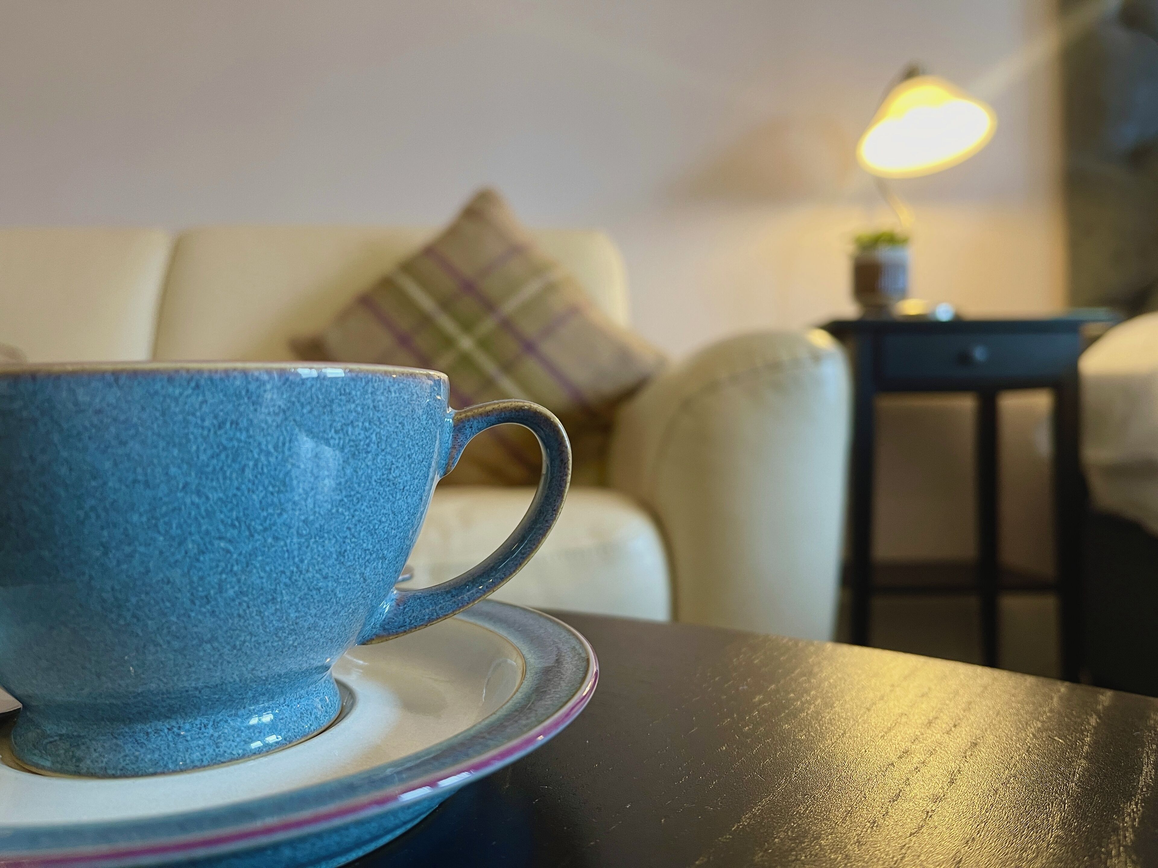 A blue ceramic cup on a saucer on a table.