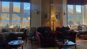 A cozy room with large windows, a fireplace, and comfortable seating. - Creag Mhor Lodge (Fort William)