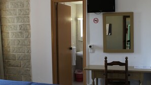 A bedroom with a bed, a desk, a chair, a television, and a bathroom visible through an open door. - Hotel Balear (Ciutadella de Menorca)