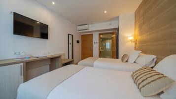 Une chambre d’hôtel avec deux lits, un bureau, un téléviseur à écran plat et un mur décoratif en bois.
