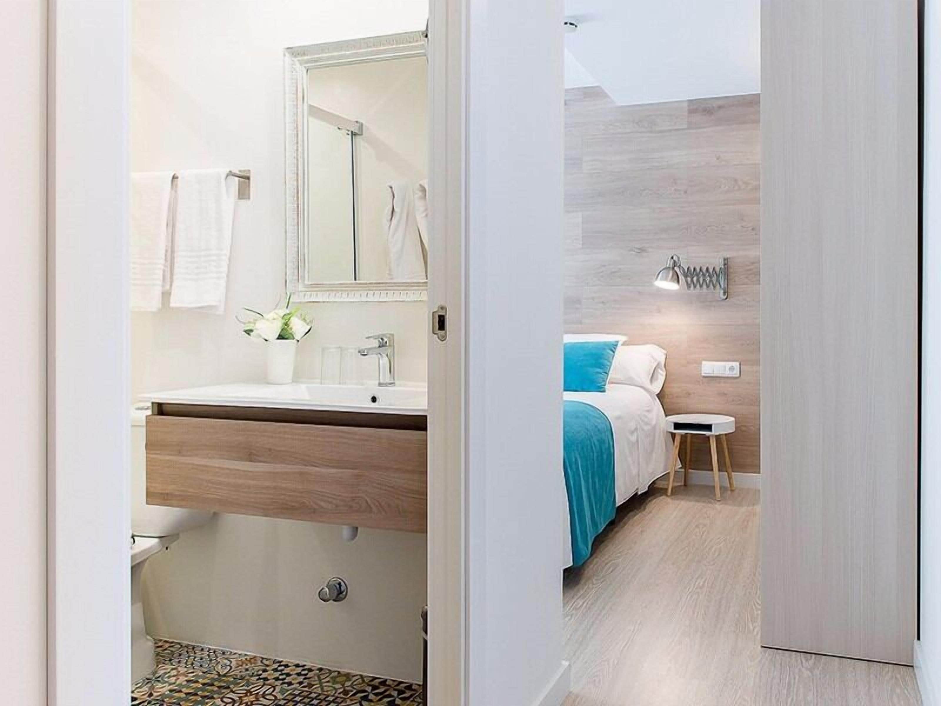 A modern bathroom with a wooden vanity, a large mirror, and a shower area.