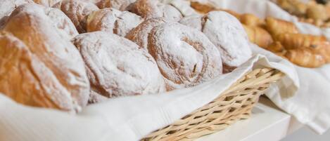 Una bandeja con pasteles, incluyendo croissants y bollos, dispuesta en una repisa.