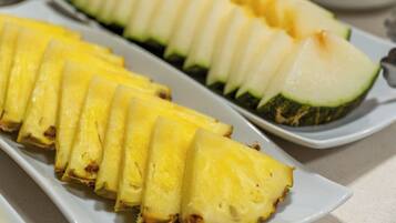 Een wit rechthoekig bord met keurig gesneden ananas en courgette.