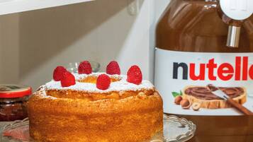 A cake on a glass stand with a jar of Nutella in the background.