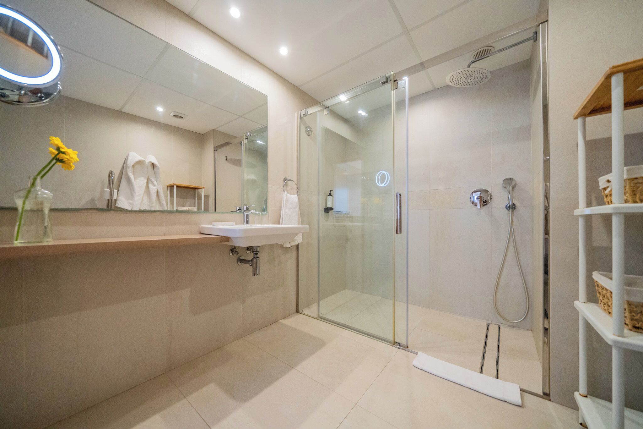 A modern bathroom with a glass-enclosed shower, a sink, and a mirror with a light.