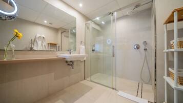 A modern bathroom with a glass-enclosed shower, a sink, and a mirror with a light.