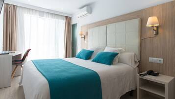 Ein Hotelzimmer mit Bett, Nachttisch und Schreibtisch mit Stuhl.