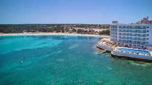 Un hotel con piscina, playa y aguas azul turquesa.