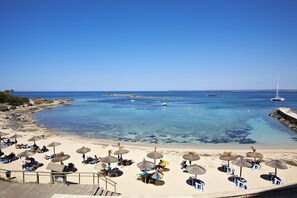 A beach with clear blue water, umbrellas, and lounge chairs. - Universal Hotel Marqués (Ses Salines)