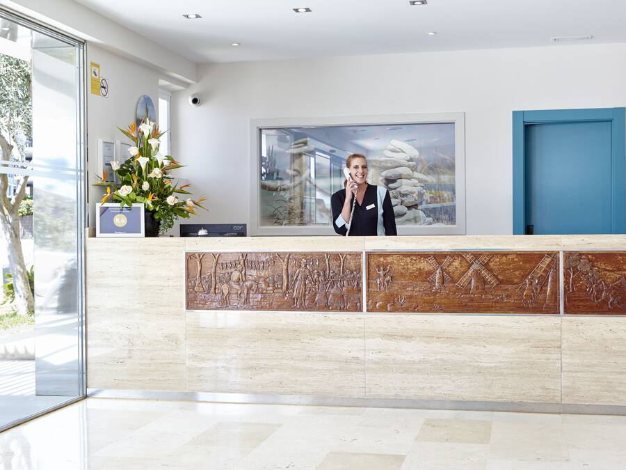 A reception desk with a large window, a blue door, and a wall-mounted phone.