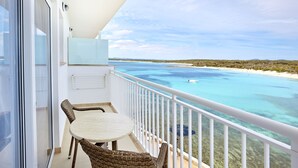 A balcony with a table and chairs, overlooking a clear blue sea and sandy beach. - Universal Hotel Marqués (Ses Salines)