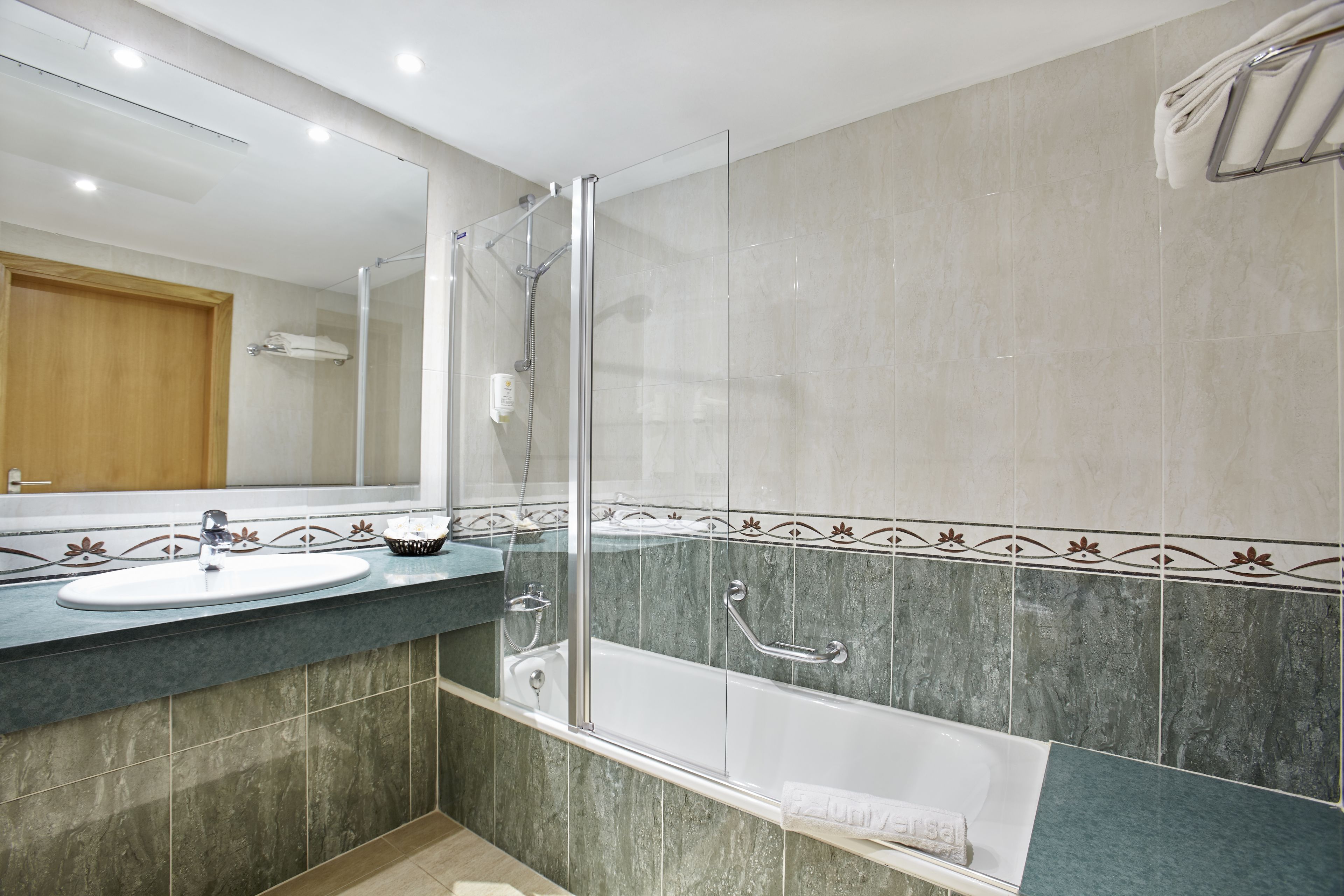 Un baño moderno con ducha envuelta en vidrio, una bañera blanca y un lavamanos con encimera de mármol.