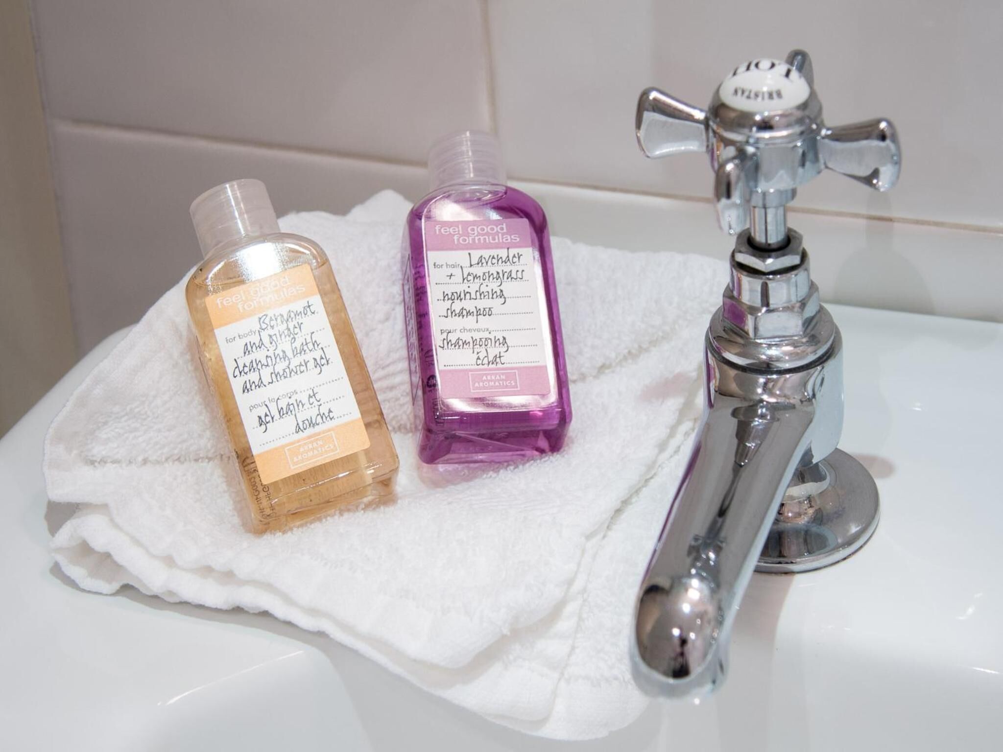 Dos botellas de jabón líquido y un grifo de baño sobre un lavabo blanco.