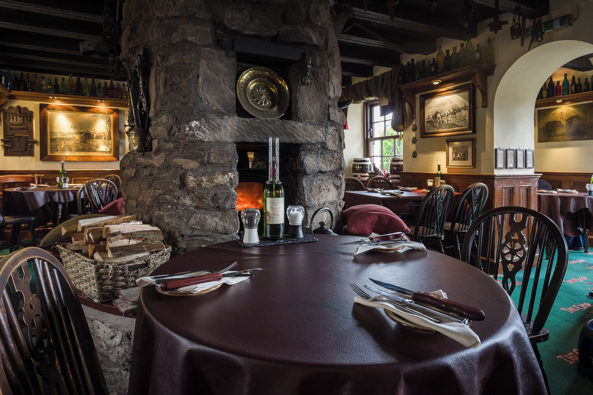 Een restaurantinterieur met stenen muren, houten tafels en stoelen.