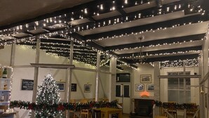 A cozy dining area with a Christmas tree, wooden tables, and chairs. - Balmoral Hotel (Moffat)
