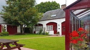 A house with a red exterior, a white door, and a green lawn. - Balmoral Hotel (Moffat)