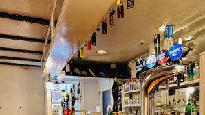 A bar area with a wooden counter, red bar stools, and a variety of beer taps including brands like Guinness and Stella Artois. - Balmoral Hotel (Moffat)