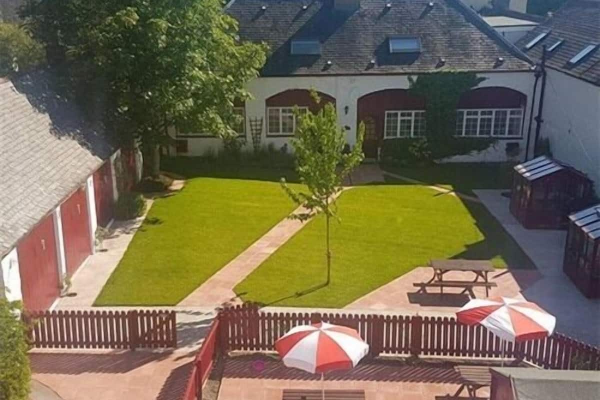 Un patio con césped, mesas de picnic y sombrillas.
