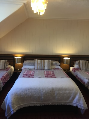 A bedroom with two beds, each with a headboard, bedside lamps, and patterned bedding. - Cameron House Hotel (Oban)