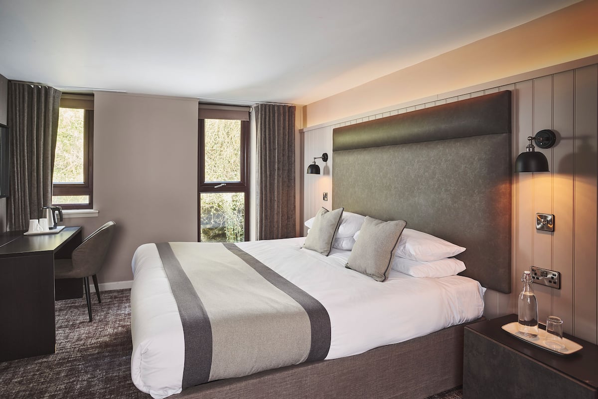A hotel room with a large bed, a desk, and a chair.
