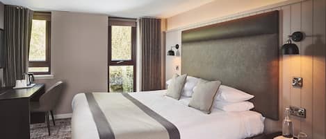 Une chambre d’hôtel avec un grand lit, un bureau et une chaise.