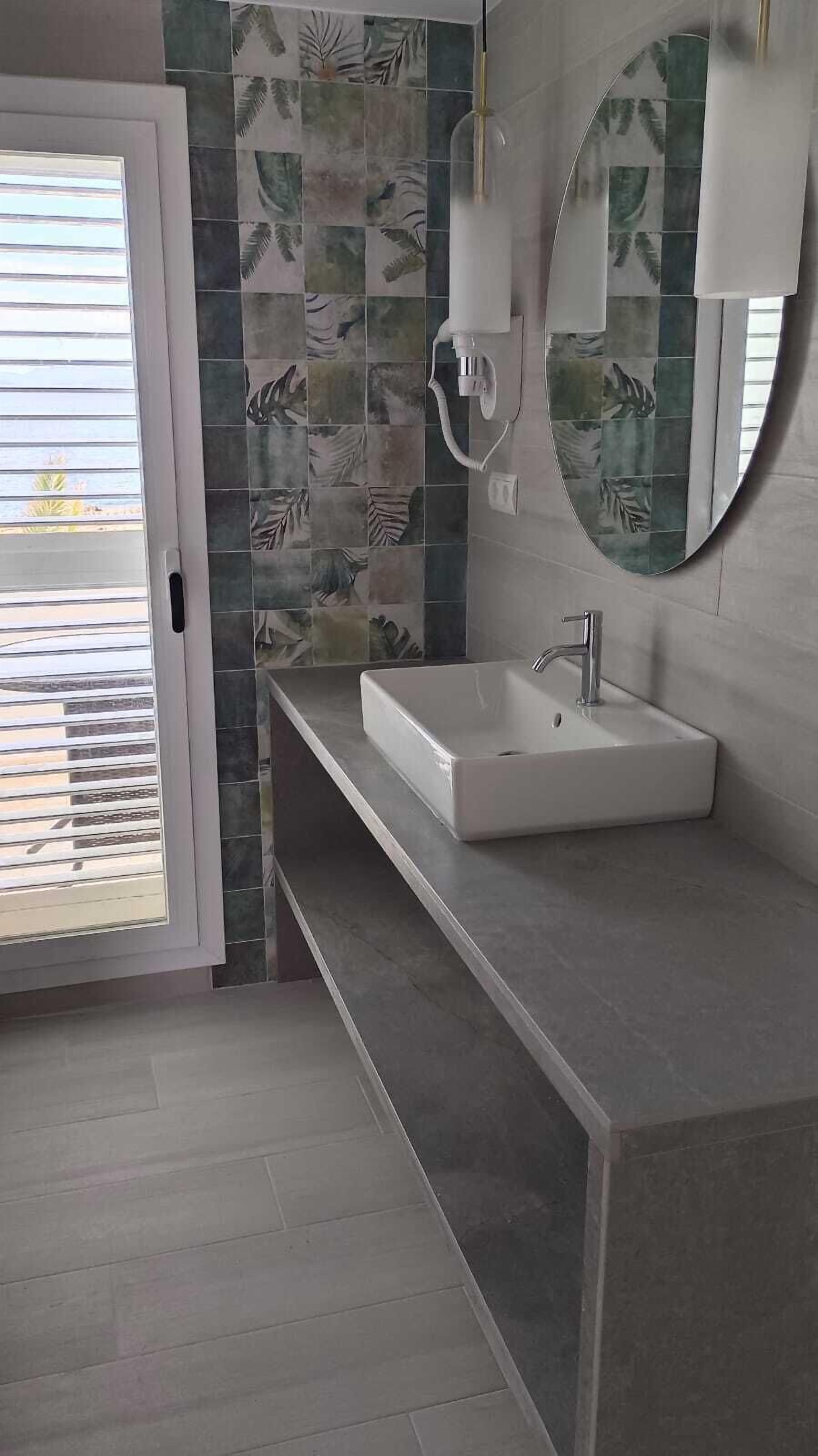 Ein Badezimmer mit einem weißen Waschbecken, einem Spiegel und einer Duschkabine.