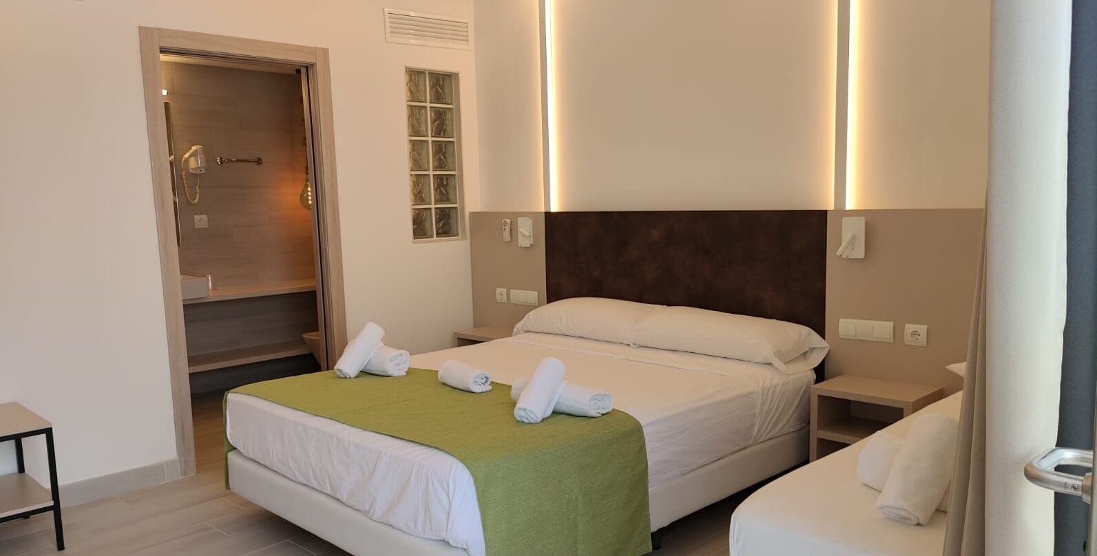 Een hotelkamer met twee bedden, een douche en een kleine tafel.