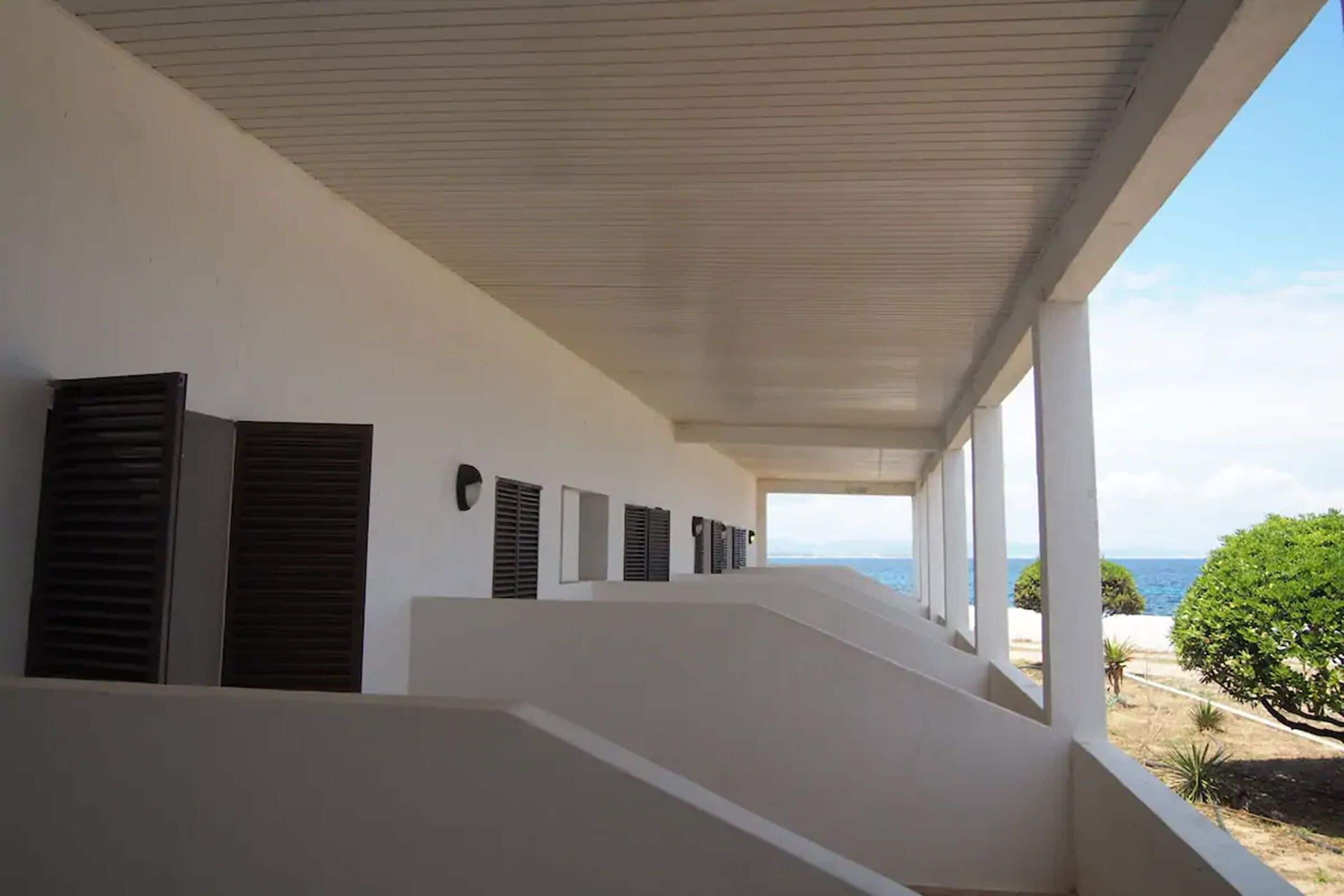A covered outdoor area with a series of windows and a view of the sea.