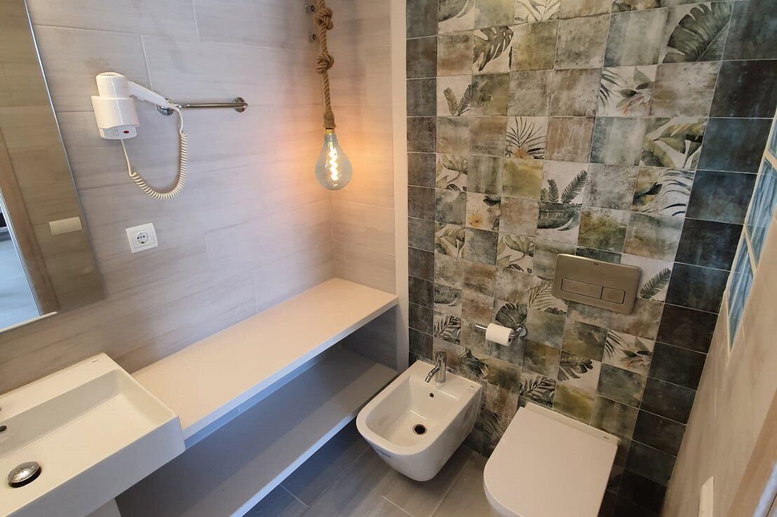 Un baño moderno con ducha, bidé e iluminación.