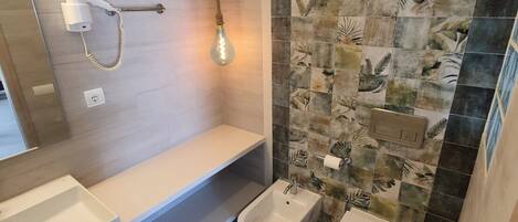 Un baño moderno con ducha, bidé e iluminación.