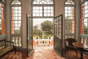 Un vano abierto que da a un jardín con una fuente, rodeado de amplias ventanas y un banco.
