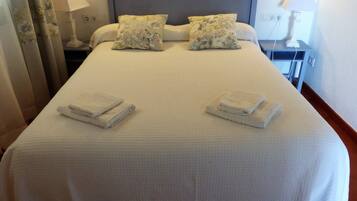 A neatly made bed with two pillows and two folded towels on the bed.