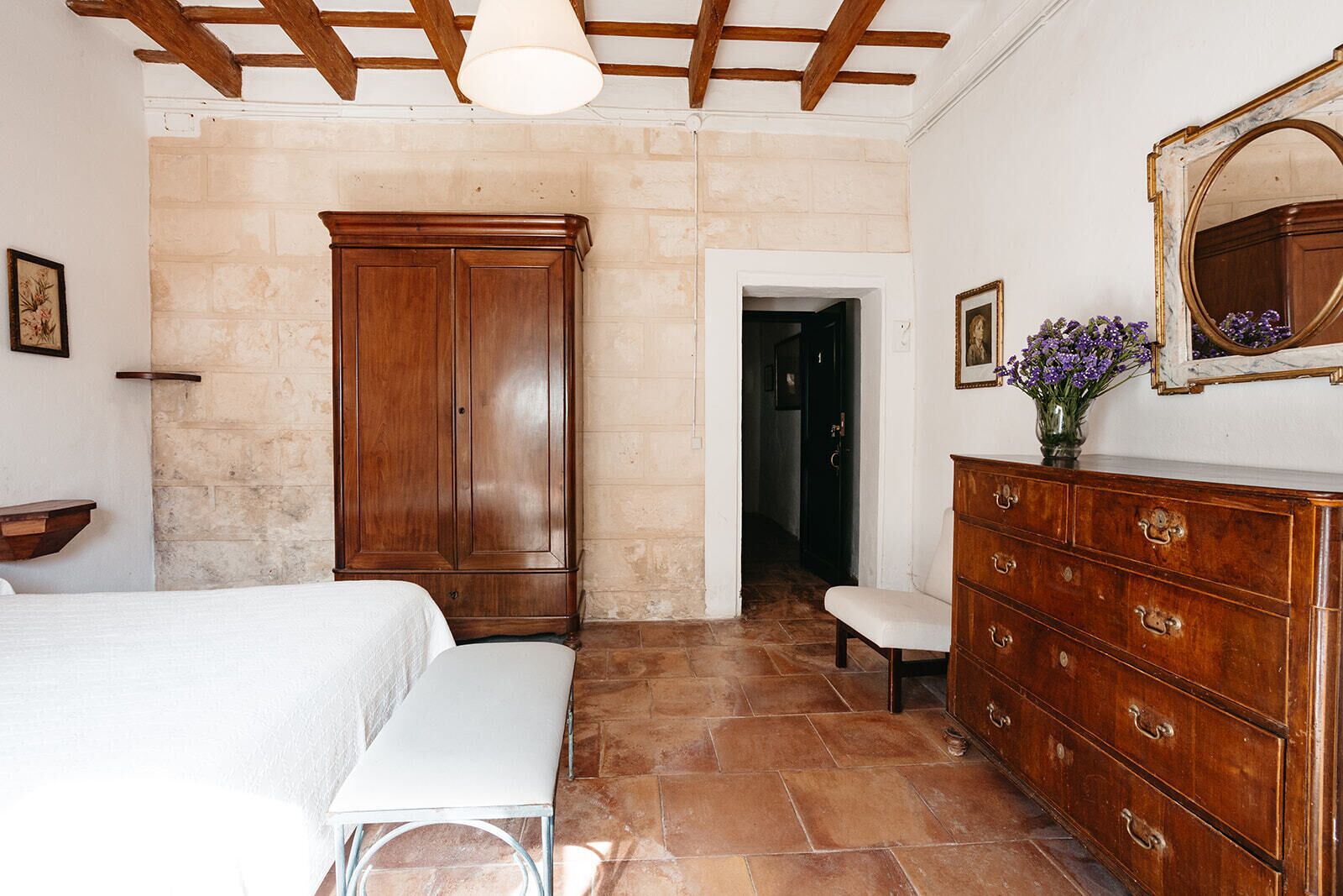 Un dormitorio con cama, cómoda, banco y armario.