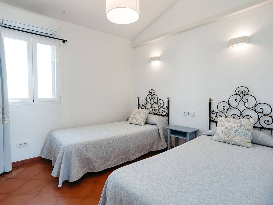 Una habitación con dos camas individuales, una mesita y una ventana con cortinas.