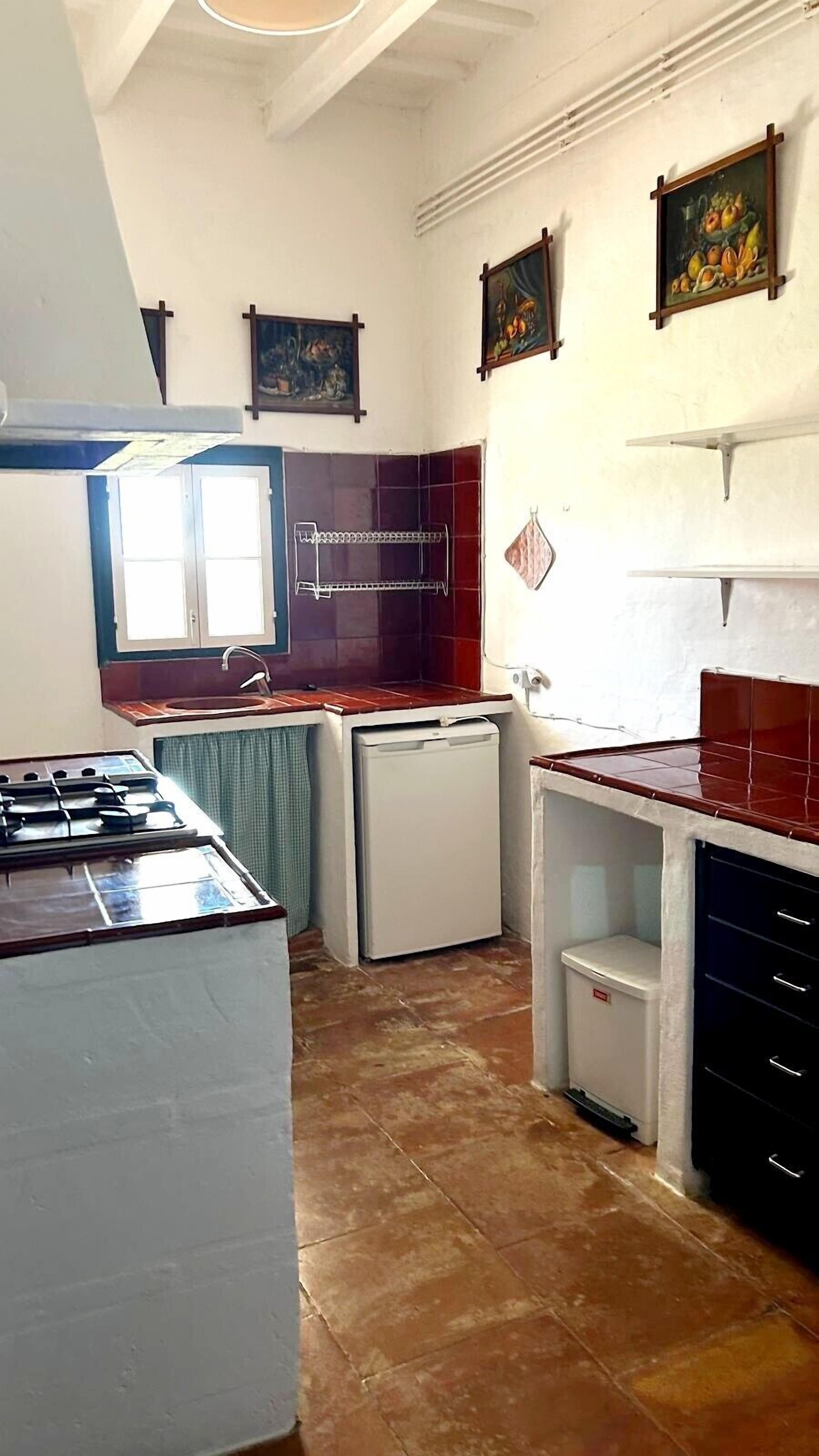 Cuina amb fogó de gas, una rentolla, nevera petita i un salvassecs de rajola.