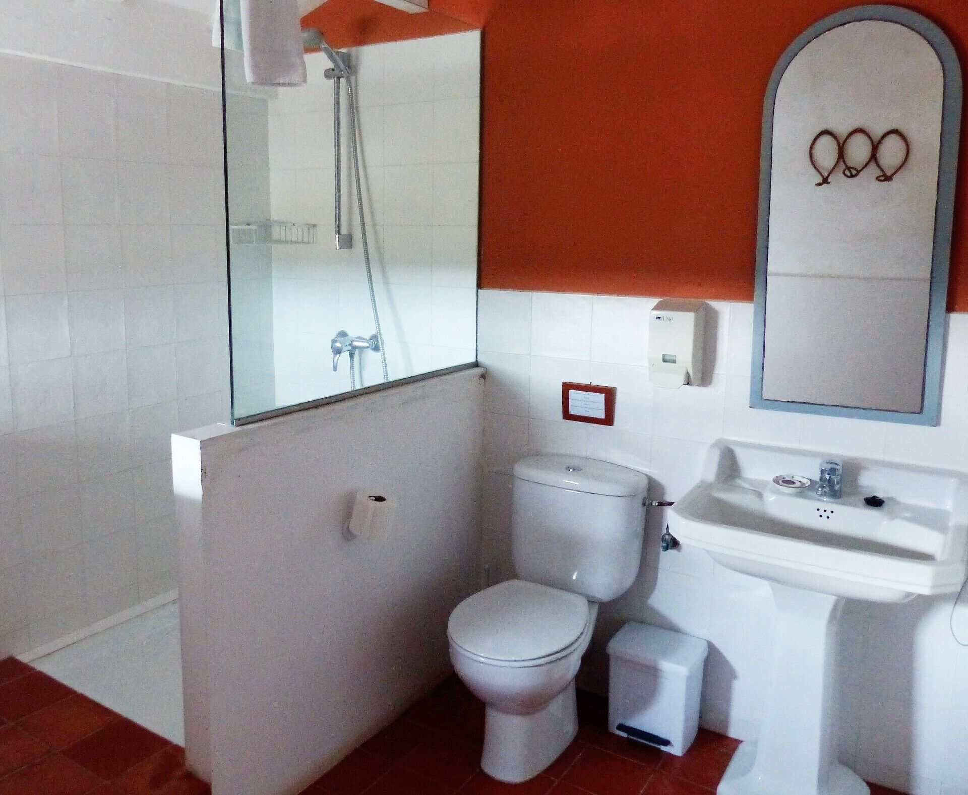Uma casa de banho com sanita, lavatório e chuveiro.