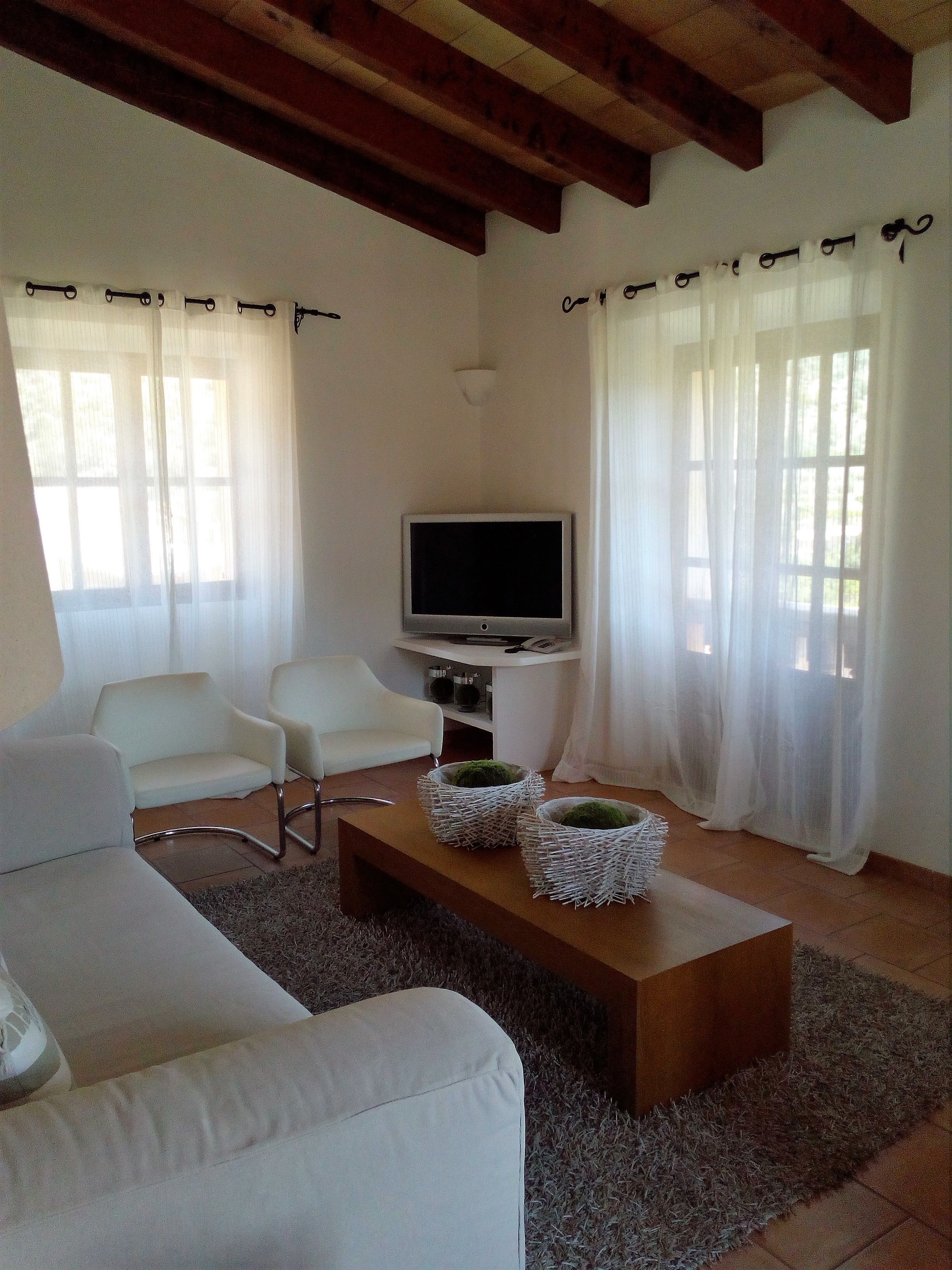 A living room with a sofa, two armchairs, a coffee table with decorative baskets, a television, and a fireplace.