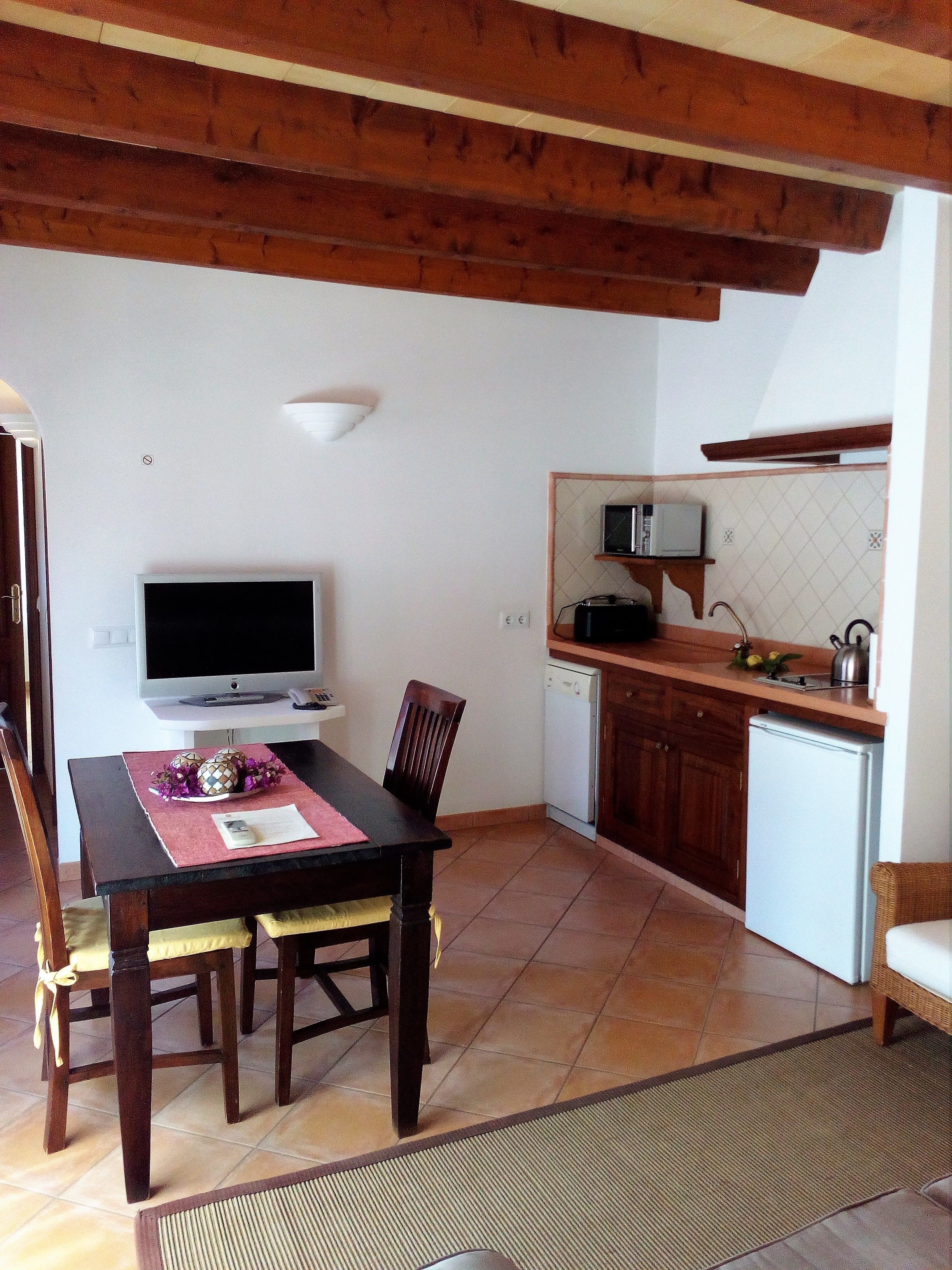 A compact kitchen with a dining area. It includes a microwave, a toaster, and a sink.