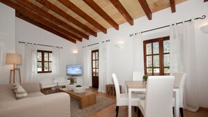 Una sala de estar con sofá, mesa de centro, televisor y comedor con sillas y una mesa.