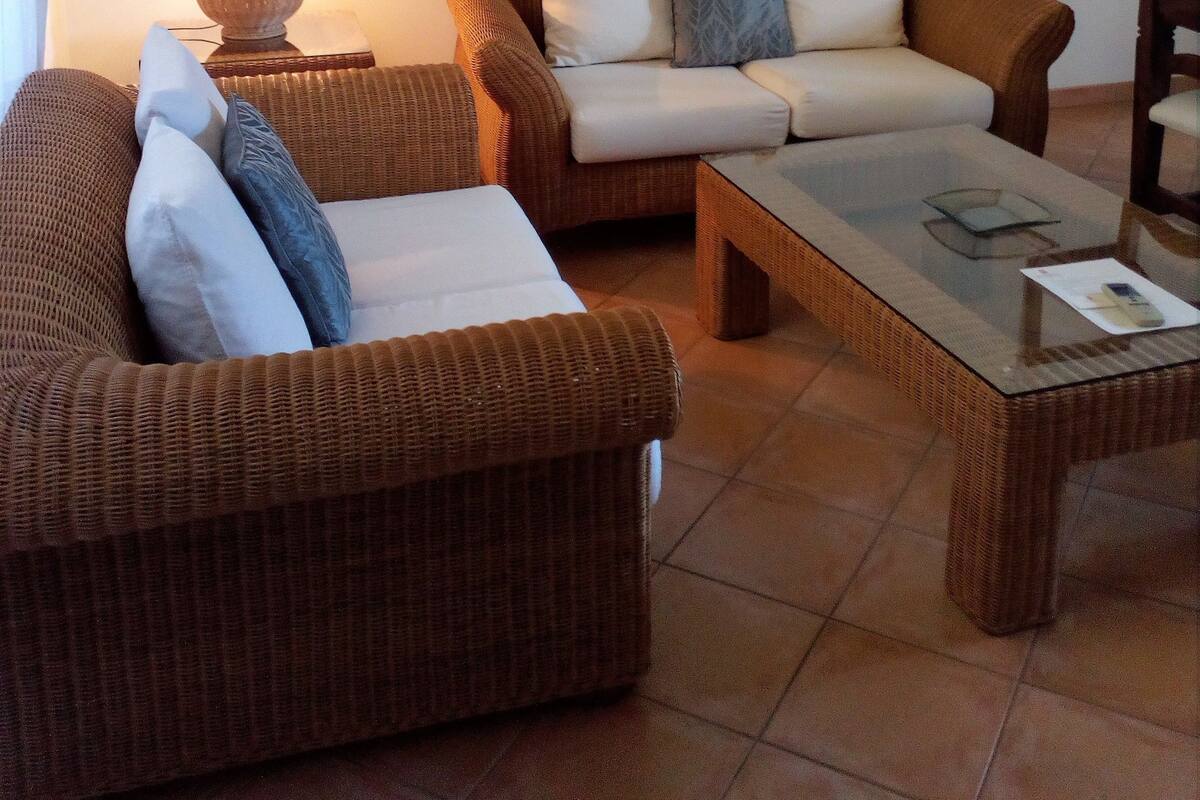 A living room with wicker furniture, a glass coffee table, and a lamp.