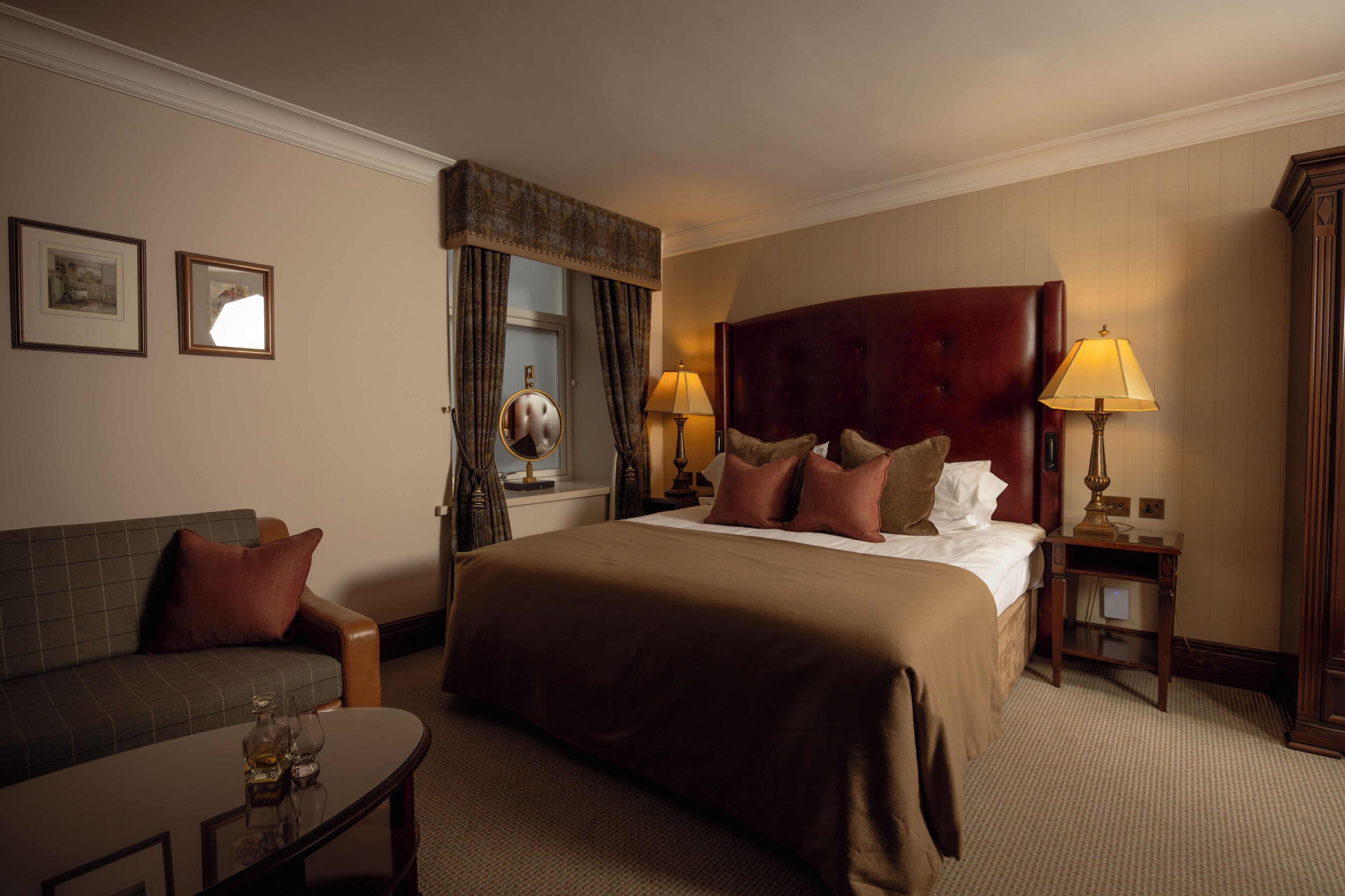 Une chambre d’hôtel avec un grand lit, un canapé, une petite table et deux lampes.