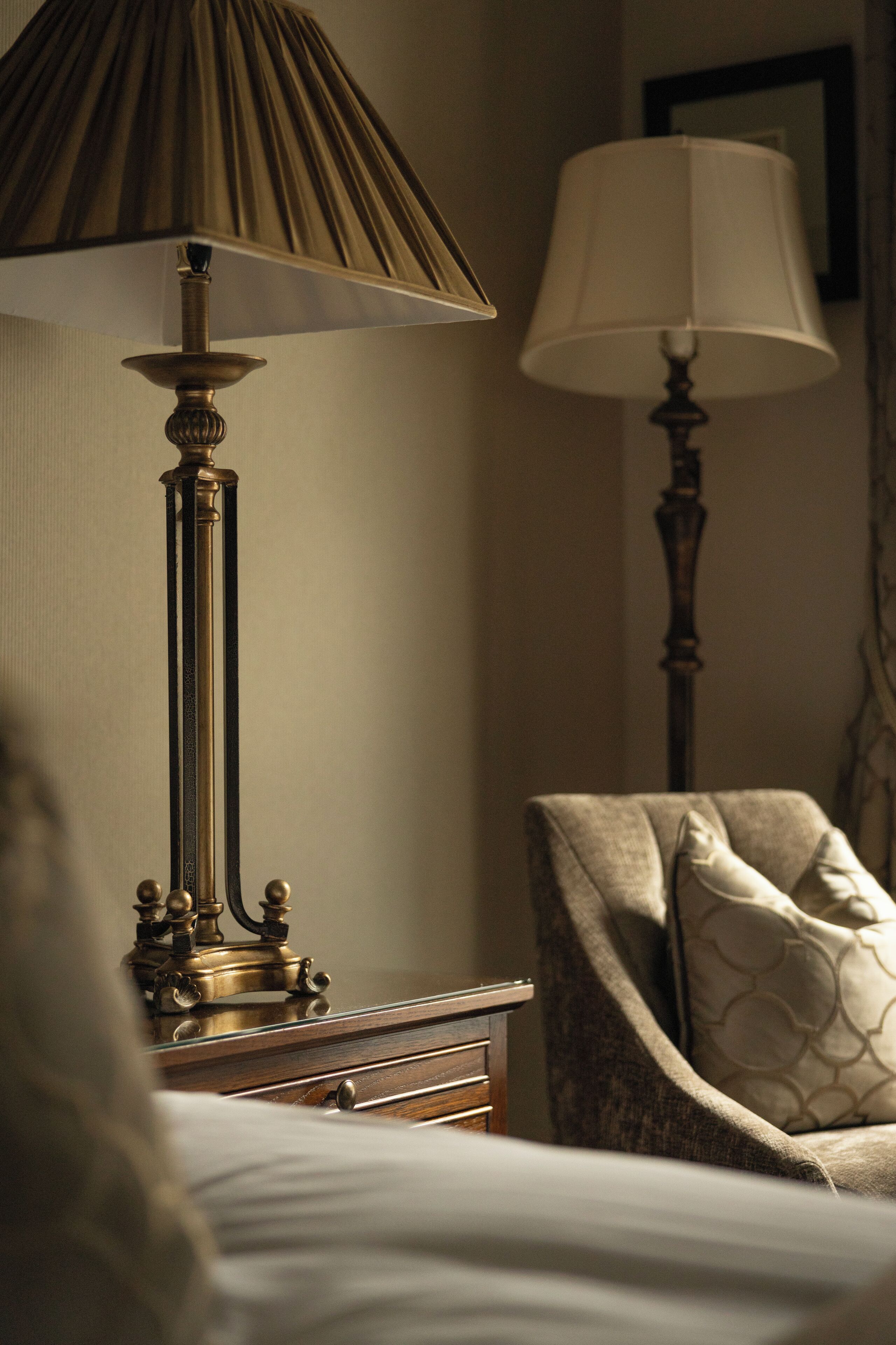 A bedroom with a bed, two bedside lamps, a chair, and a nightstand.