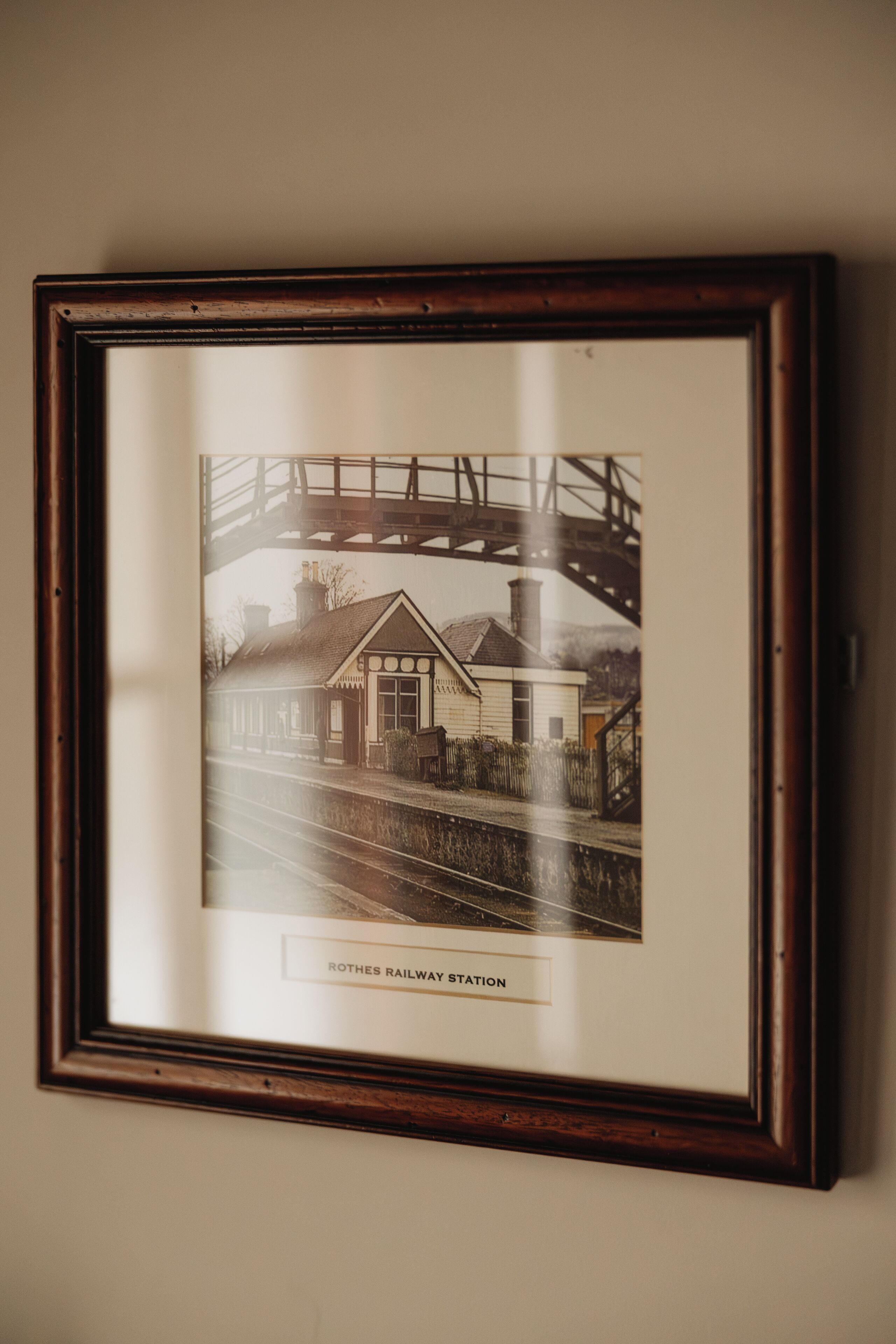 A framed photograph of a railway station with a bridge in the background.