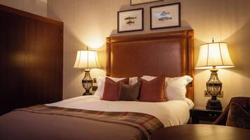 Quarto de hotel com uma cama grande, duas luminárias de cabeceira, um painel de cabeceira de madeira e dois quadros na parede.
