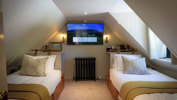 A bedroom with two beds, a TV mounted on the wall, and a radiator.