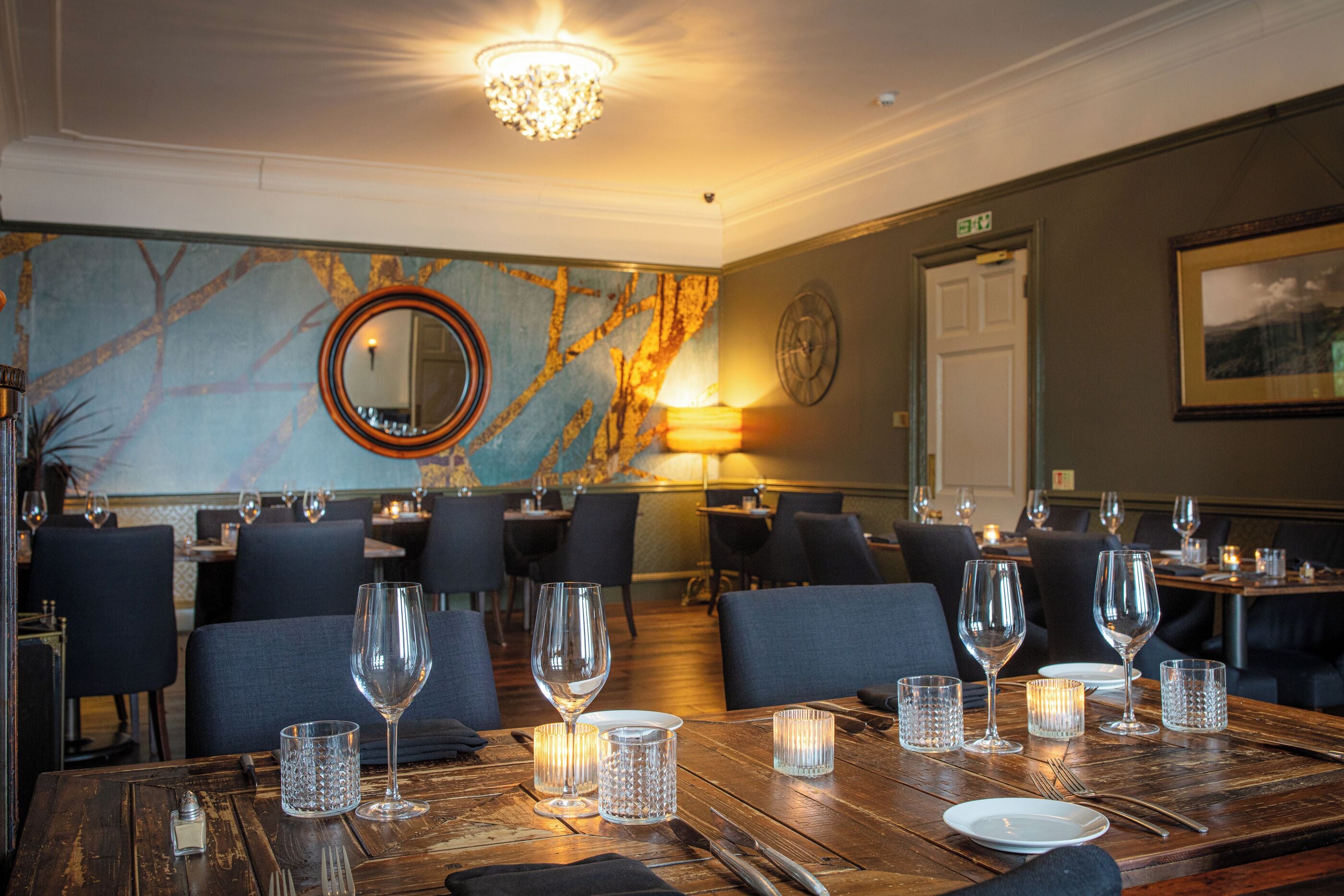 A restaurant with wooden tables set for dining, featuring clear glassware and candles.