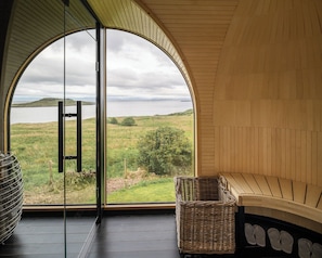 A room with a large arched window overlooking a grassy landscape and water. - The Flodigarry Hotel in the Skye  (Staffin)