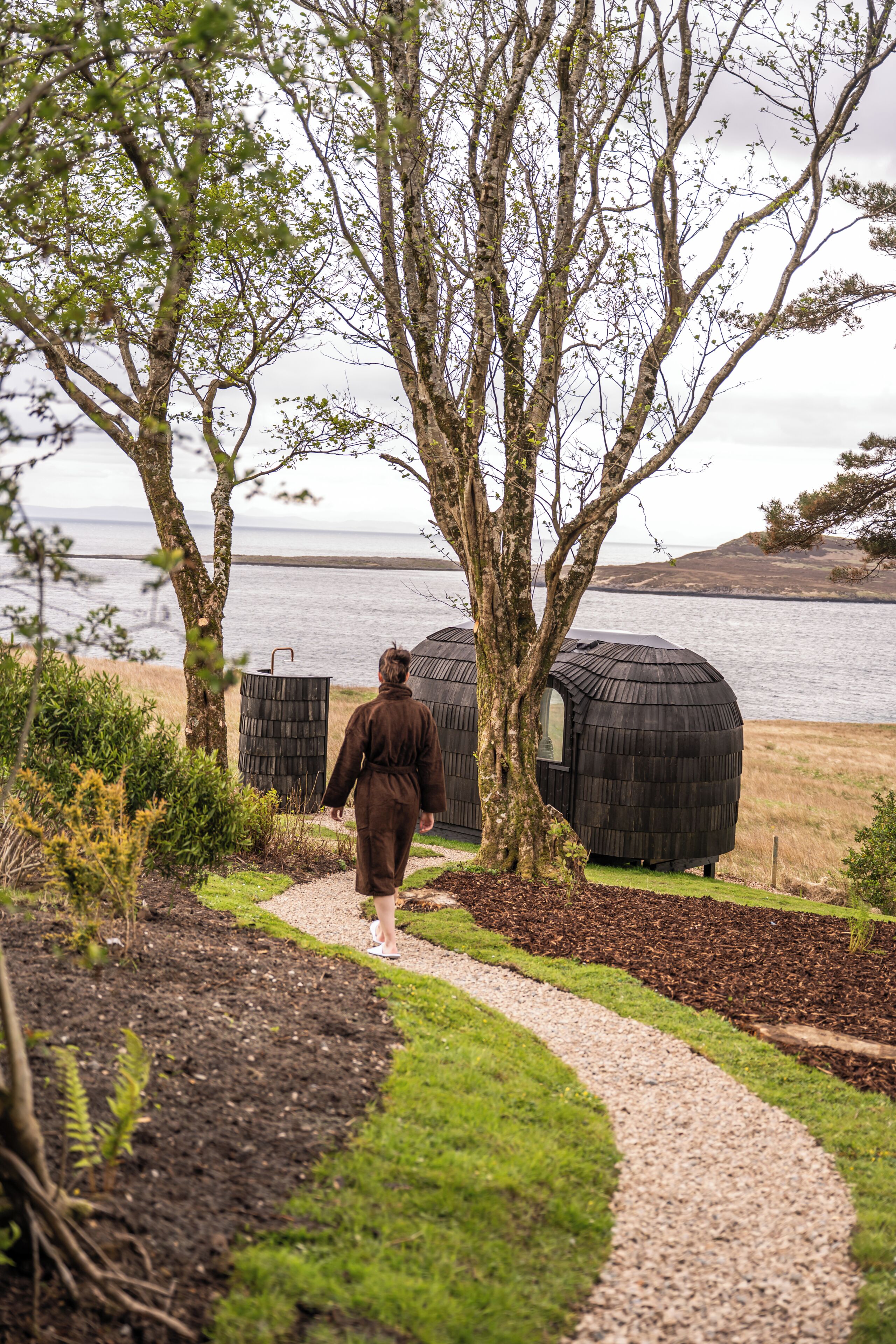 A pathway leading to a rustic wooden structure by a body of water.