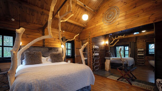 A log cabin bedroom with a large bed, a second bed, a sitting area, and a bathroom. - The Flodigarry Hotel in the Skye  (Staffin)