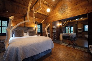 A log cabin bedroom with a large bed, a second bed, a sitting area, and a bathroom. - The Flodigarry Hotel in the Skye  (Staffin)